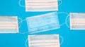 Coronavirus protection. Many antiviral protective medical face masks with ear loops spread out on a blue background. Surgical mask Royalty Free Stock Photo
