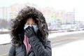 Coronavirus protection woman in medical mask and fur hood standing on winter street Royalty Free Stock Photo