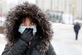 Coronavirus protection  woman in medical mask and fur hood standing on winter street Royalty Free Stock Photo