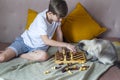 Coronavirus quarantine. Activity of kids of home. Stay home. Young boy playing chess whith the cat at home during quarantine