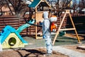 Coronavirus quarantine. man wearing protective hazmat suit spraying disinfectant and chemicals.