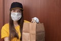 Coronavirus and quarantine. Safe food delivery from restaurants, cafes, pizzerias. Young woman courier in uniform in a medical Royalty Free Stock Photo
