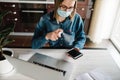 Coronavirus. Sanitizer. Business woman working in home, wearing protective mask in quarantine. Cleaning hands mobile phone to Royalty Free Stock Photo