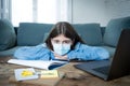 Coronavirus school closures and lockdown. Bored kid with face mask studying online class at home Royalty Free Stock Photo