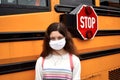 Coronavirus school reopening concept: girl with face mask by school bus