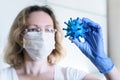 Coronavirus and science concept, woman researcher holds corona virus in hand, scientific and medical research during COVID-19