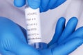 Coronavirus test sample or Covid-19 vial held between the blue gloved hands of a lab technician Royalty Free Stock Photo