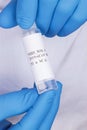 Coronavirus test sample or Covid-19 vial held between the blue gloved hands of a lab technician Royalty Free Stock Photo