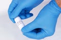 Coronavirus test sample or Covid-19 vial held between the blue gloved hands of a lab technician Royalty Free Stock Photo