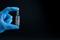 Coronavirus vaccine concept, cure for COVID-19. Blue hand glove holds ampoule with drug against SARS-CoV-2 Royalty Free Stock Photo
