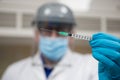 Coronavirus vaccine dose ready for immunisation. Doctor with gloved hands holding a hyperdermic needle and vaccination dose