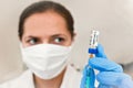 Coronavirus vaccine label own design, not real product injected into syringe hold by hand with blue gloves, blurred nurse face