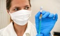 Coronavirus vaccine label own design, not real product injected into syringe hold by hand with blue gloves, blurred nurse face