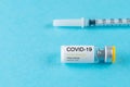 Coronavirus vaccine vial glass with a syringe on blue background.  Covid-19 medicine vaccination concept. World pandemic concept Royalty Free Stock Photo