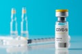 Coronavirus vaccine vial glass with a syringe on blue background. Covid-19 medicine vaccination concept. World pandemic concept