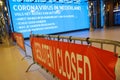 Coronavirus warning alert on electronic billboard in a Dutch train station with barriers blocking entry