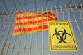 Coronavirus warning sign on the barbed wire fence near flag of Catalonia, an autonomous community in Spain. COVID-19