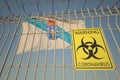 Coronavirus warning sign on the barbed wire fence near flag of Galicia, an autonomous community in Spain. COVID-19