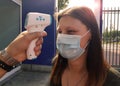 Coronavirus woman whose fever is measured with digital thermometer at the entrance of an outdoor place