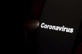 `Coronavirus` word glowing on a black screen and fingertip pointing at it. Concept for mourning and being in a spotlight