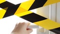 Coronavirus yellow tape Stay home. A hand reaches for the door handle