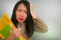 Corporate business stress portrait of young attractive upset and stressed executive Asian Chinese woman tired and unhappy holding Royalty Free Stock Photo