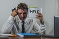 Corporate business worker in stress - young attractive stressed and desperate businessman holding help sign overworked and Royalty Free Stock Photo