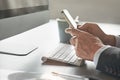 Corporate communication. a businessmans hands using his cellphone in the office.