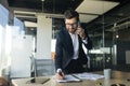 Corporate communication. Happy male manager working with papers and talking on cellphone, taking notes in office Royalty Free Stock Photo