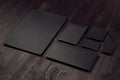 Corporate identity set of blank black letterhead, envelope, notepad, business card on dark wood board, inclined.