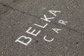 Corporate inscription of Russian car-sharing company BELKA CAR on asphalt indicates the parking place. Car rental is available