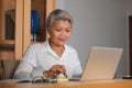 Corporate job lifestyle portrait of happy and successful attractive middle aged Asian woman working at office laptop computer desk