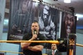 Corporate Kane talks into mic with arms crossed in ring