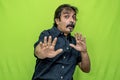 A corporate man in a black shirt flails his hands and contorts his face in terror while standing against a green screen Royalty Free Stock Photo