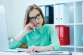 Serious young attractive business woman in glasses sitting at office chair working at desktop computer talking on mobile Royalty Free Stock Photo