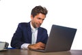 Corporate portrait of young attractive and efficient business man working at office laptop computer desk confident in elegant suit