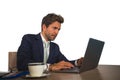 Corporate portrait of young attractive and efficient business man working at office laptop computer desk confident in elegant suit