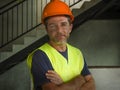 Corporate portrait of young attractive and happy builder man or constructor posing confident smiling wearing building helmet and