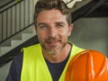 Corporate portrait of young attractive and happy builder man or constructor posing confident smiling wearing building helmet and Royalty Free Stock Photo