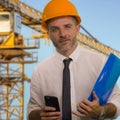 Corporate portrait of young attractive and successful engineer man or architect working on building at construction site wearing Royalty Free Stock Photo