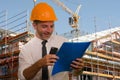 Corporate portrait of young attractive and successful engineer man or architect working on building at construction site wearing Royalty Free Stock Photo