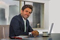 Corporate portrait of young happy handsome and attractive businessman working at computer desk in modern office at central busines Royalty Free Stock Photo