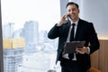 Smiling skilled businessman talking phone while looking at data. Ornamented. Royalty Free Stock Photo