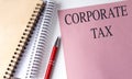 CORPORATE TAX text on pink paper with notebooks Royalty Free Stock Photo