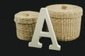 Corporeal Letter A uppercase white matte and wood with two wicker baskets on black background