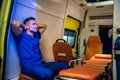 Corpsman in a blue uniform sitting in the ambulance car with his hands on the nape
