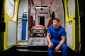 Corpsman in a blue uniform sitting in an ambulance car and thinking