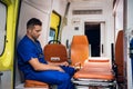 Corpsman in a blue uniform sitting inside the ambulance car and thinking of something