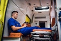 Corpsman in medical uniform sits with phone in his hands in the ambulance car