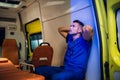 Corpsman sits inside the ambulance car and puts his hands on head and looks somewhere